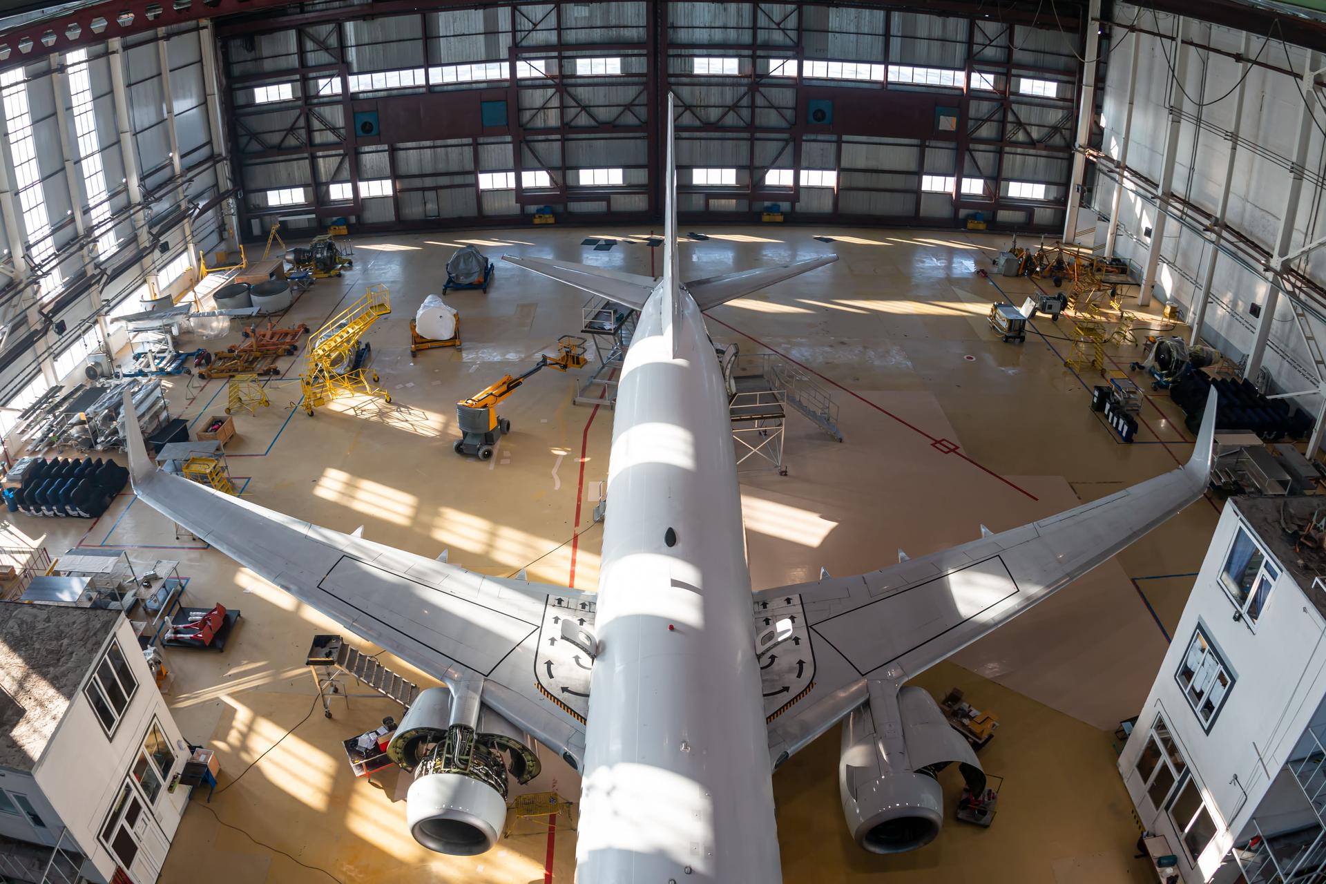 Top view of a white passenger jet plane in the aviation hangar