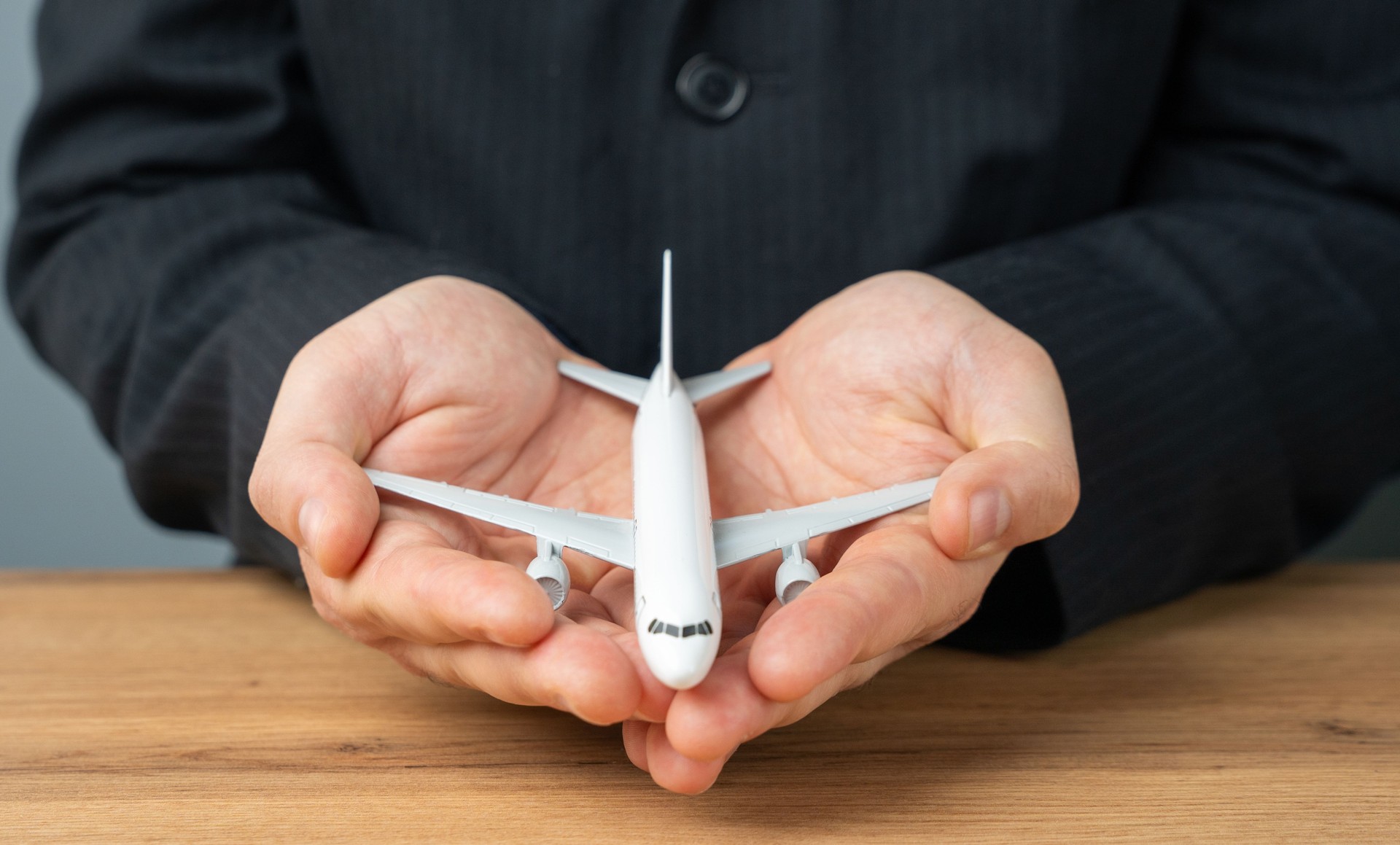 An airline plane in the palms of a businessman or official. Aircraft leasing and insurance by airlines. The importance of air travel. Investments in the air transport industry.