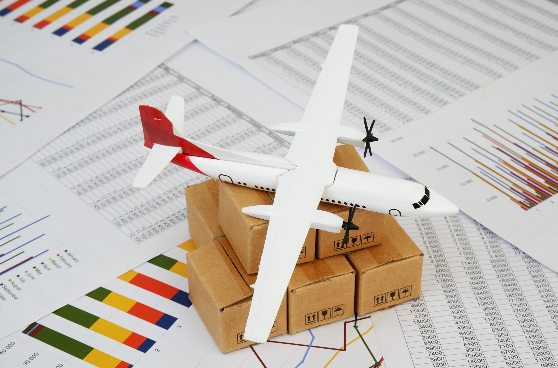 Airplane on shipping carton boxes on financial documents close up.